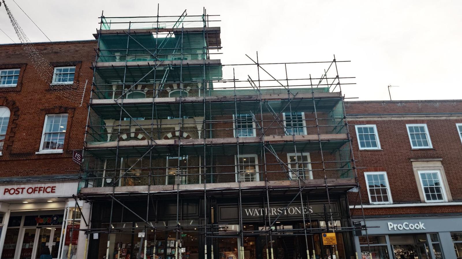 Façade Scaffolding, Guildford High Street - Armstrong Scaffolding Armstrong Scaffolding full height façade scaffold with debris netting above the Waterstones shopfront on Guildford High Street